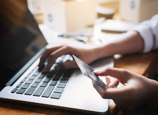 Hand holding credit card over laptop