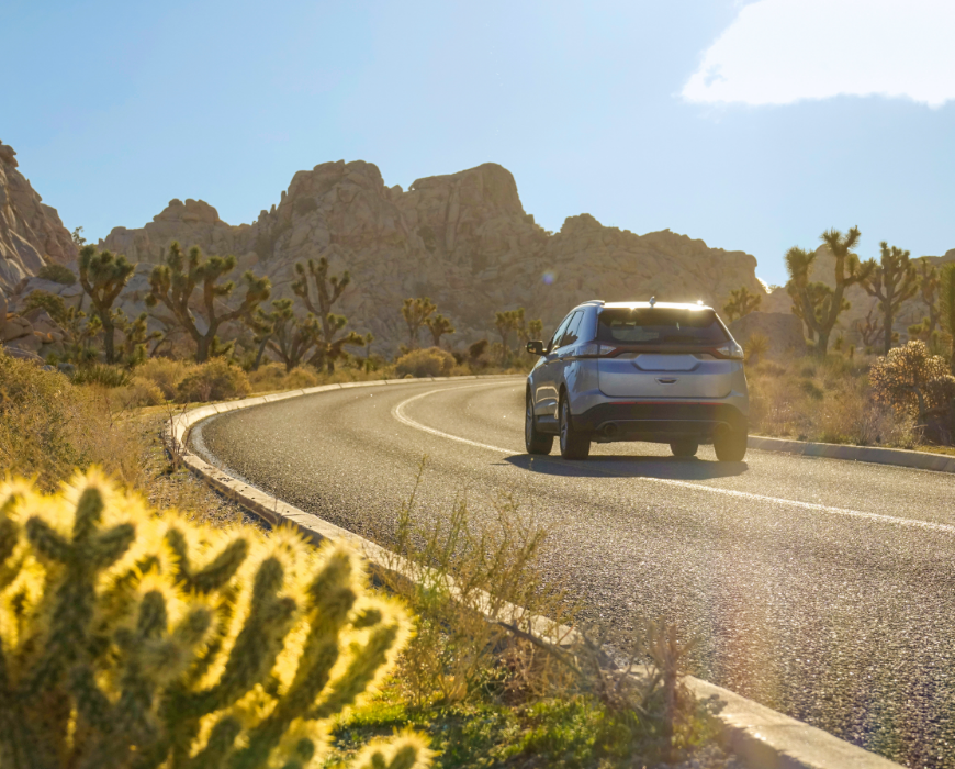 vehicle driving down road in desert